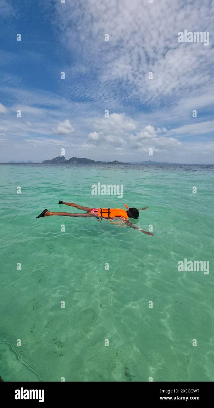 Eine Frau schwimmt friedlich auf einem Surfbrett im Meer und nimmt die Ruhe des Wassers unter sich Stockfoto