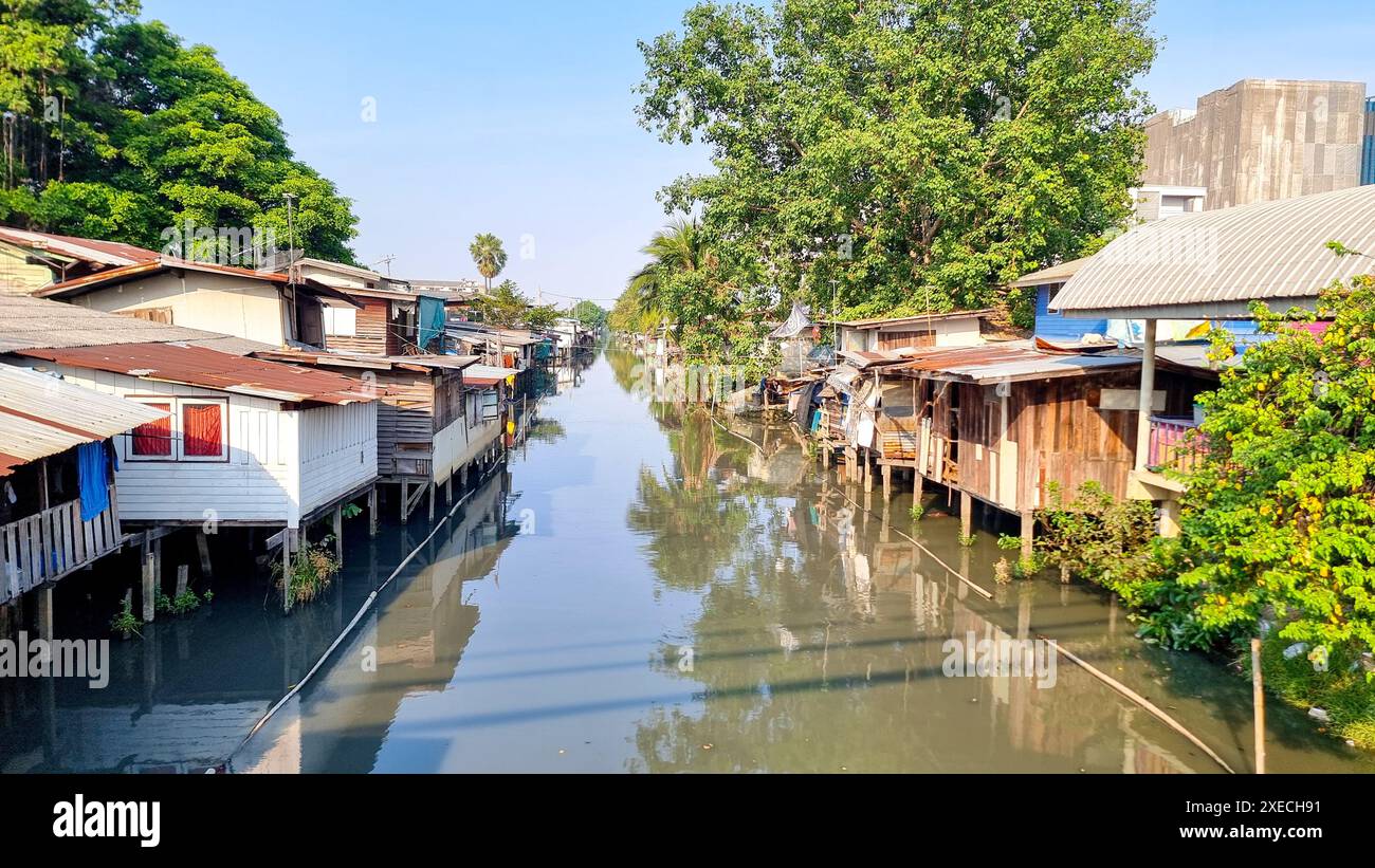 Ein ruhiger Fluss, der sich durch üppiges Grün schlängelt, mit malerischen Häusern an seinen Ufern, die eine malerische Flusslandschaft schaffen Stockfoto