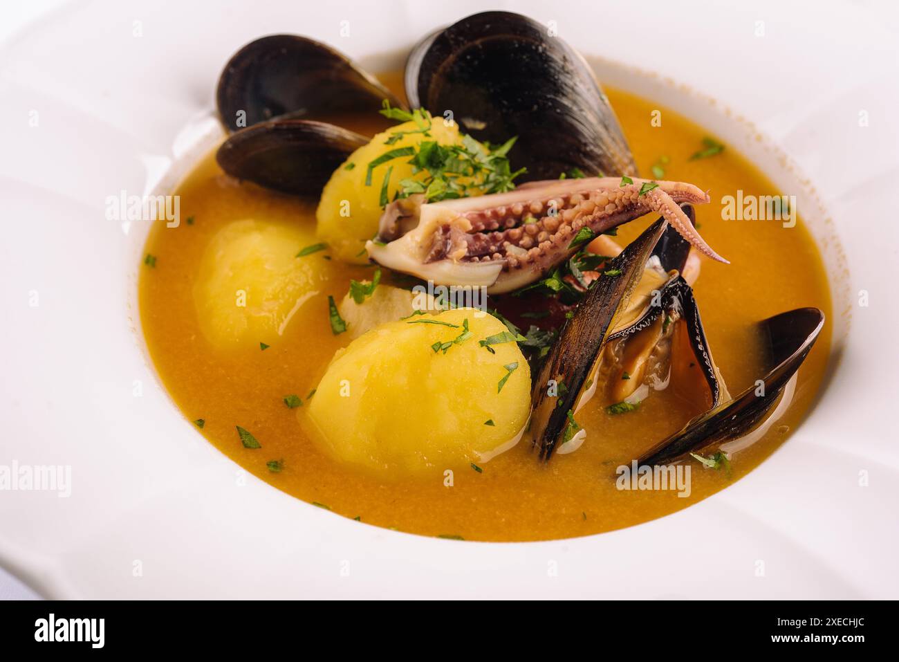 Cremige Meeresfrüchte-Suppe mit Muscheln, Kartoffeln und kleinen Tintenfischen Stockfoto