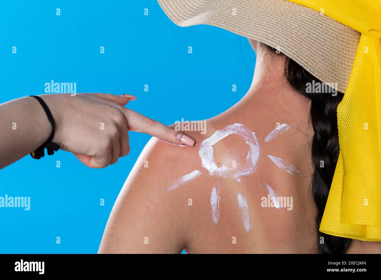 Eine Freundin ölt den Rücken ihrer Freundin mit einer Sonnencreme, während sie das Sonnensymbol macht. Stockfoto