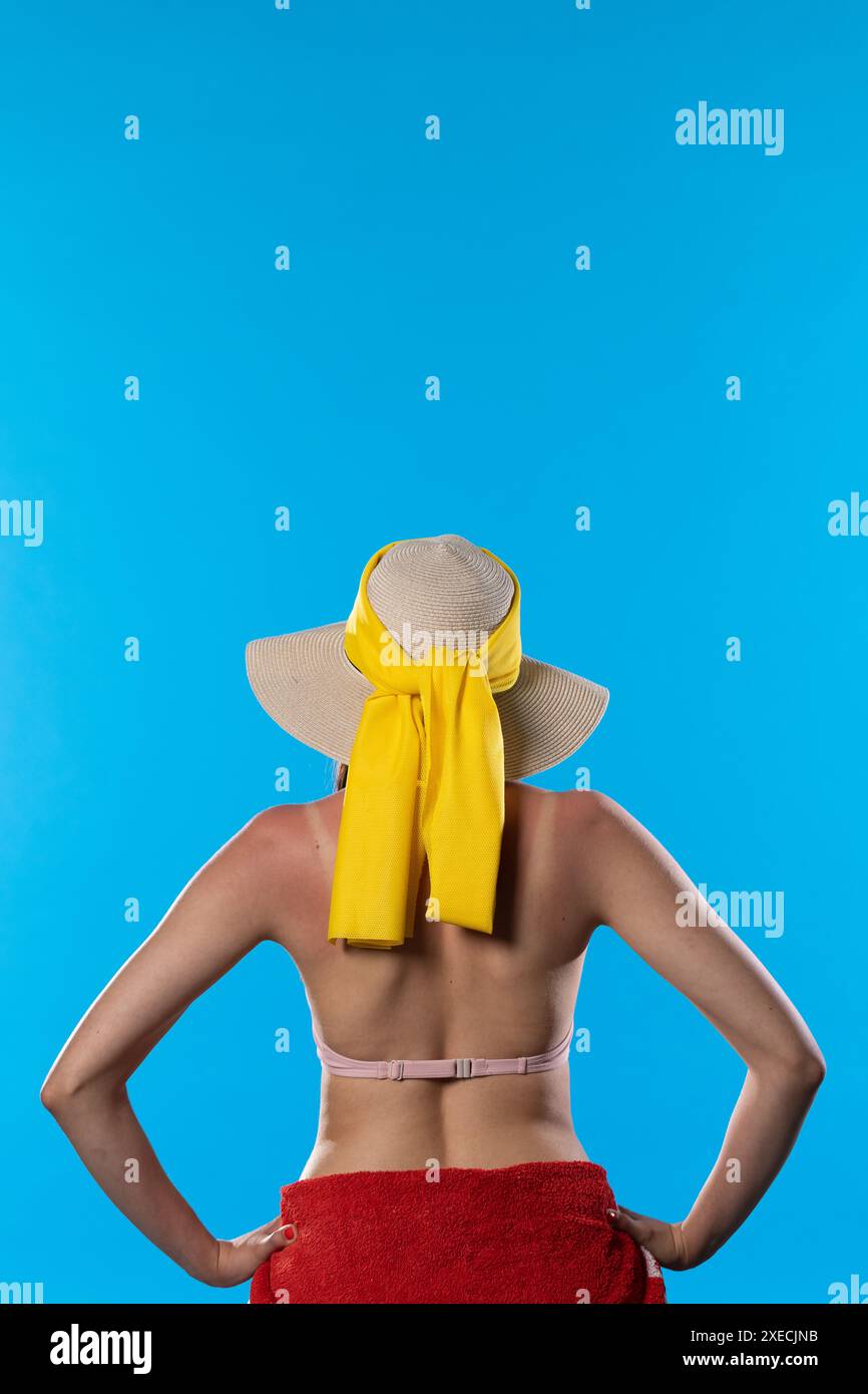Eine Frau mit einem großen Strandhut hält ihre Hände an ihren Hüften. Stockfoto
