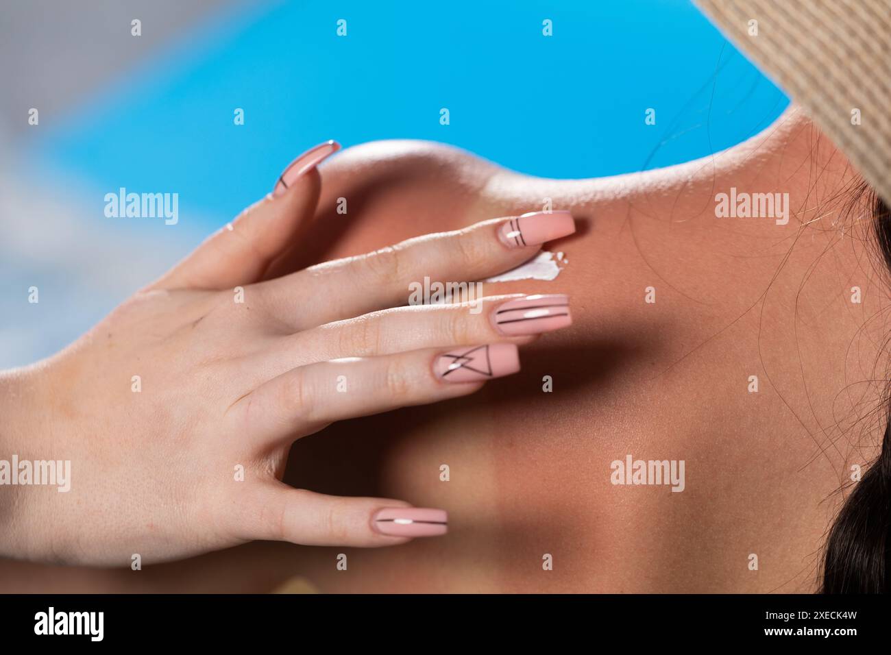 Eine Freundin ölt den Rücken ihrer Freundin mit einer Sonnencreme, während sie das Sonnensymbol macht. Stockfoto