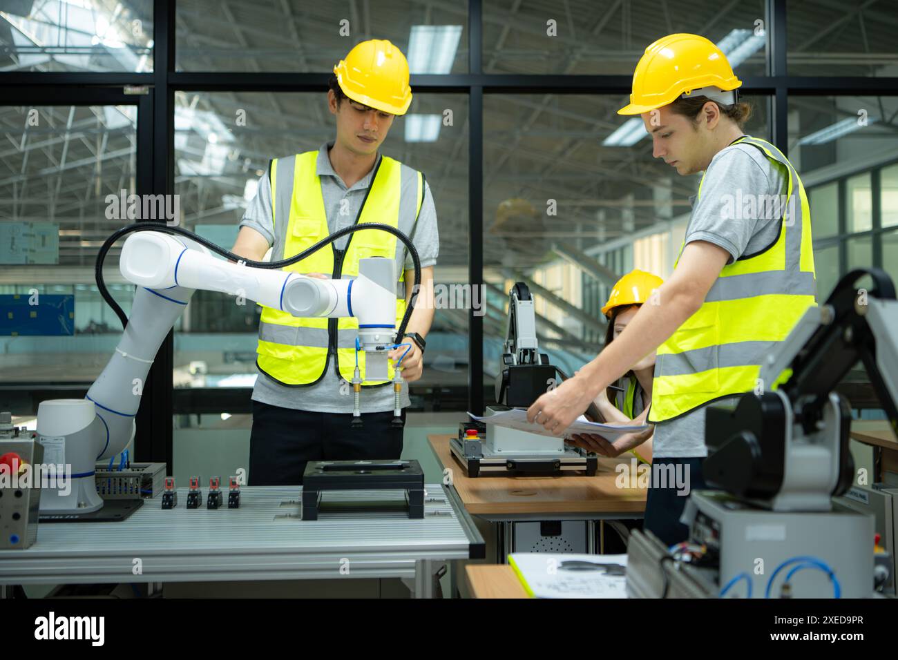 Gruppe von Ingenieuren und Technikern, die die Technologie zur Steuerung von Handrobotern für den industriellen Einsatz erlernen. Stockfoto