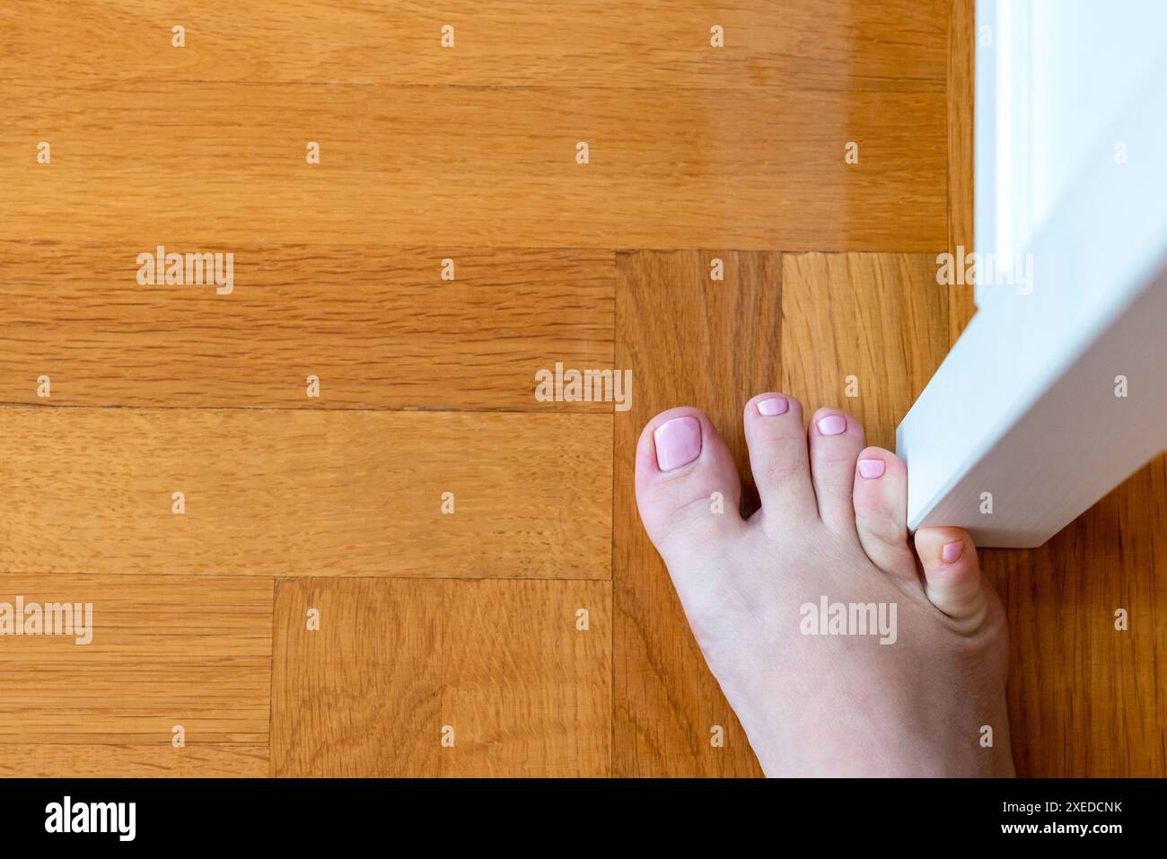 Frau schlug mit dem kleinen Zeh auf die Möbel. Zwischenfall zu Hause. Verletzung des kleinen Fingers des Fußes Stockfoto