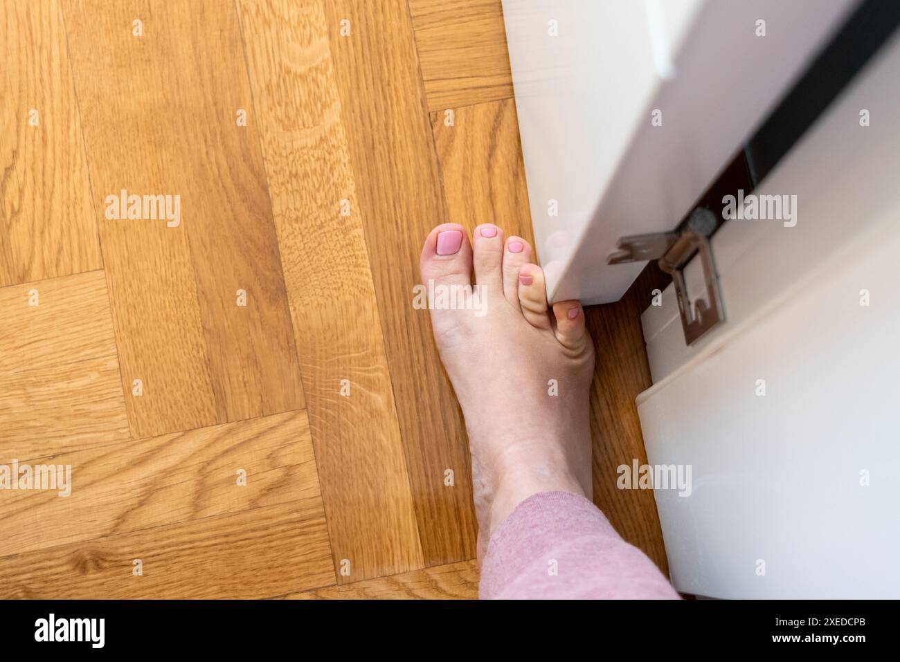 Frau schlug mit dem kleinen Zeh auf die Möbel. Zwischenfall zu Hause. Verletzung des kleinen Fingers des Fußes Stockfoto