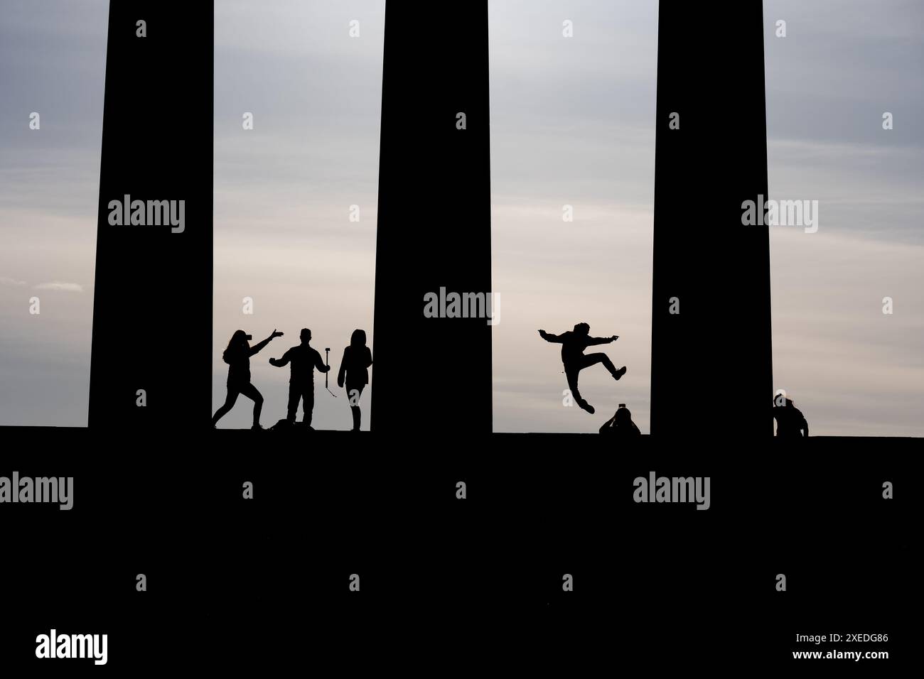 Silhouette junger Menschen in choreografischen Posen zwischen Säulen des National Monument of Scotland auf dem Calton Hill in Edinburgh, Schottland, Stockfoto