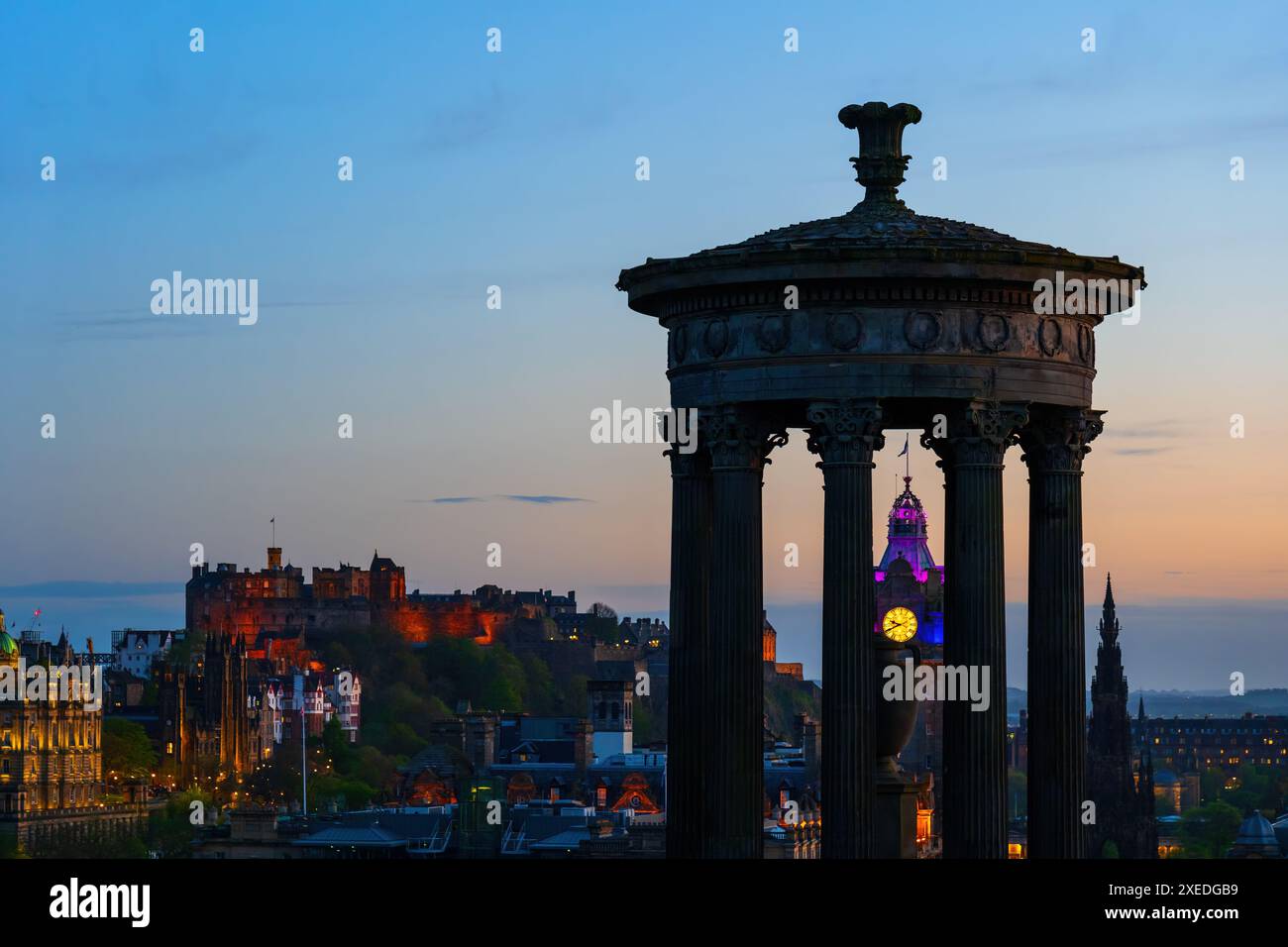 Dugald Stewart Monument, das das Balmoral Hotel umrahmt und Edinburgh Castle in der Abenddämmerung in der Stadt Edinburgh in Schottland, Großbritannien. Stockfoto