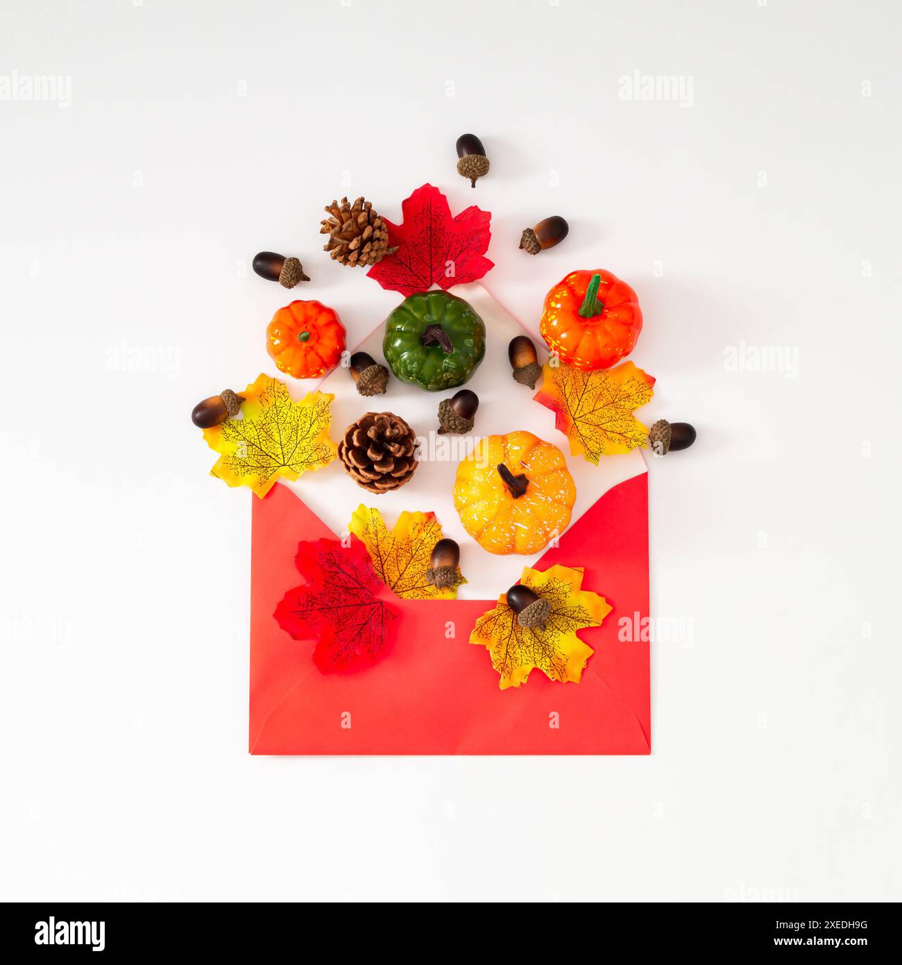Herbstblätter, Kürbisse, Tannenzapfen und Nüsse aus rotem Umschlag auf weißem Hintergrund. Minimales Herbst- oder Herbstkonzept. Saisonale Natur flach gelegen. Stockfoto