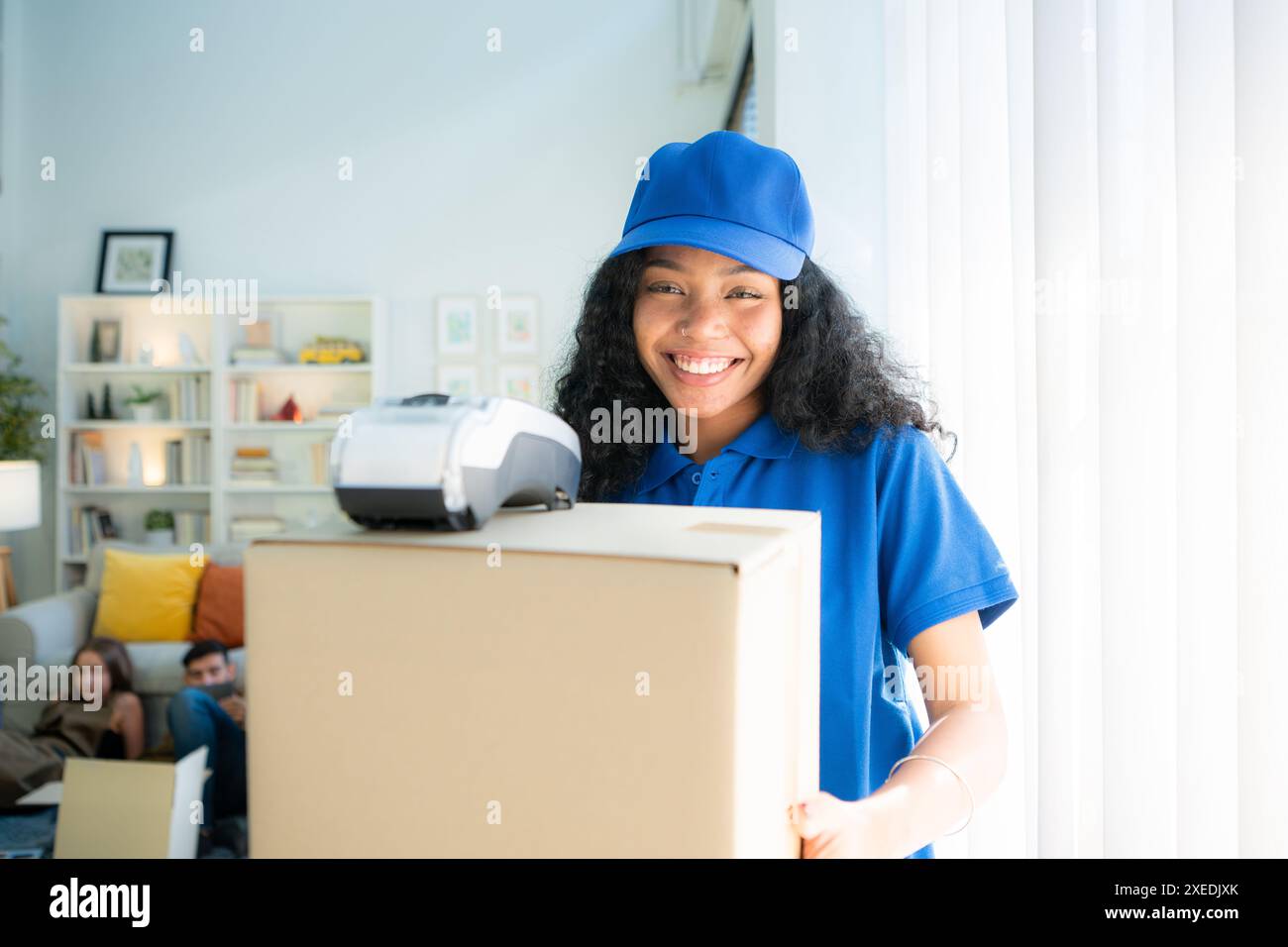 Porträt einer lächelnden Frau, die eine Box hält und zu Hause in die Kamera schaut Stockfoto