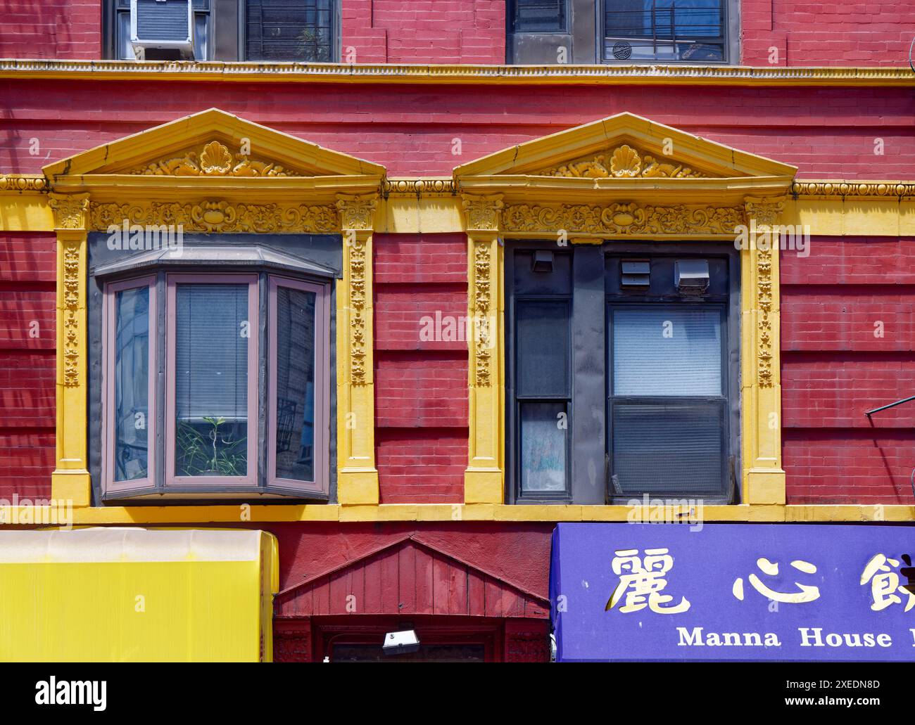 NYC Chinatown: 125 Mott Street, ein sechsstöckiges, begehbares Wohnhaus, ist kühn mit roten Backsteinen und gelben Terracotta über den Straßenläden bemalt. Stockfoto