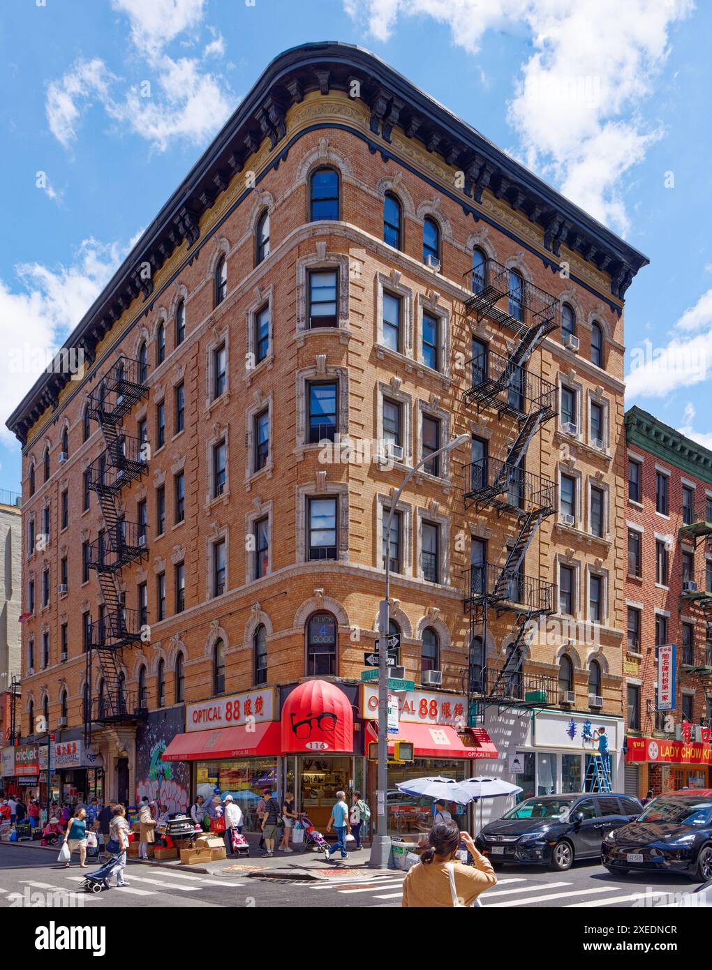 NYC Chinatown: 116 Mott Street, ein sechsstöckiges, begehbares Apartmentgebäude, hat eine abgerundete Ecke und weiße Terracotta-Details an der orangen Backsteinfassade. Stockfoto