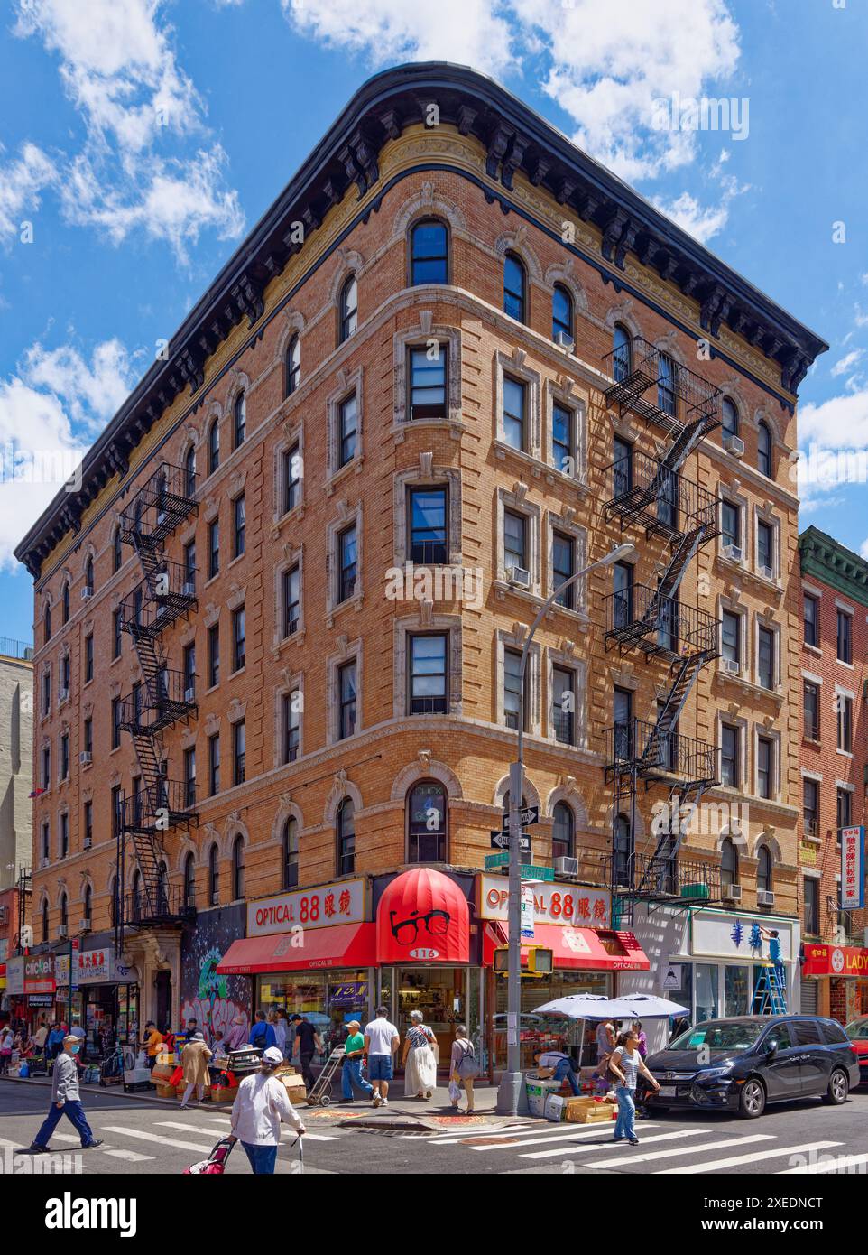 NYC Chinatown: 116 Mott Street, ein sechsstöckiges, begehbares Apartmentgebäude, hat eine abgerundete Ecke und weiße Terracotta-Details an der orangen Backsteinfassade. Stockfoto