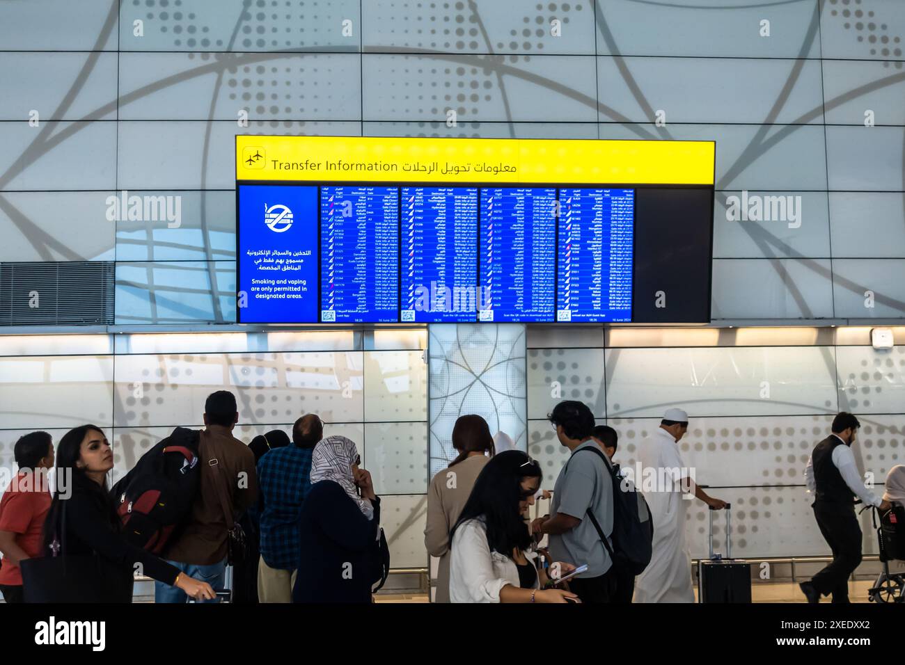 Touristen, die Informationen zum Transfer, Informationen zum Flugbildschirm, Flughafen Zayed, Abu Dhabi, Vereinigte Arabische Emirate suchen Stockfoto