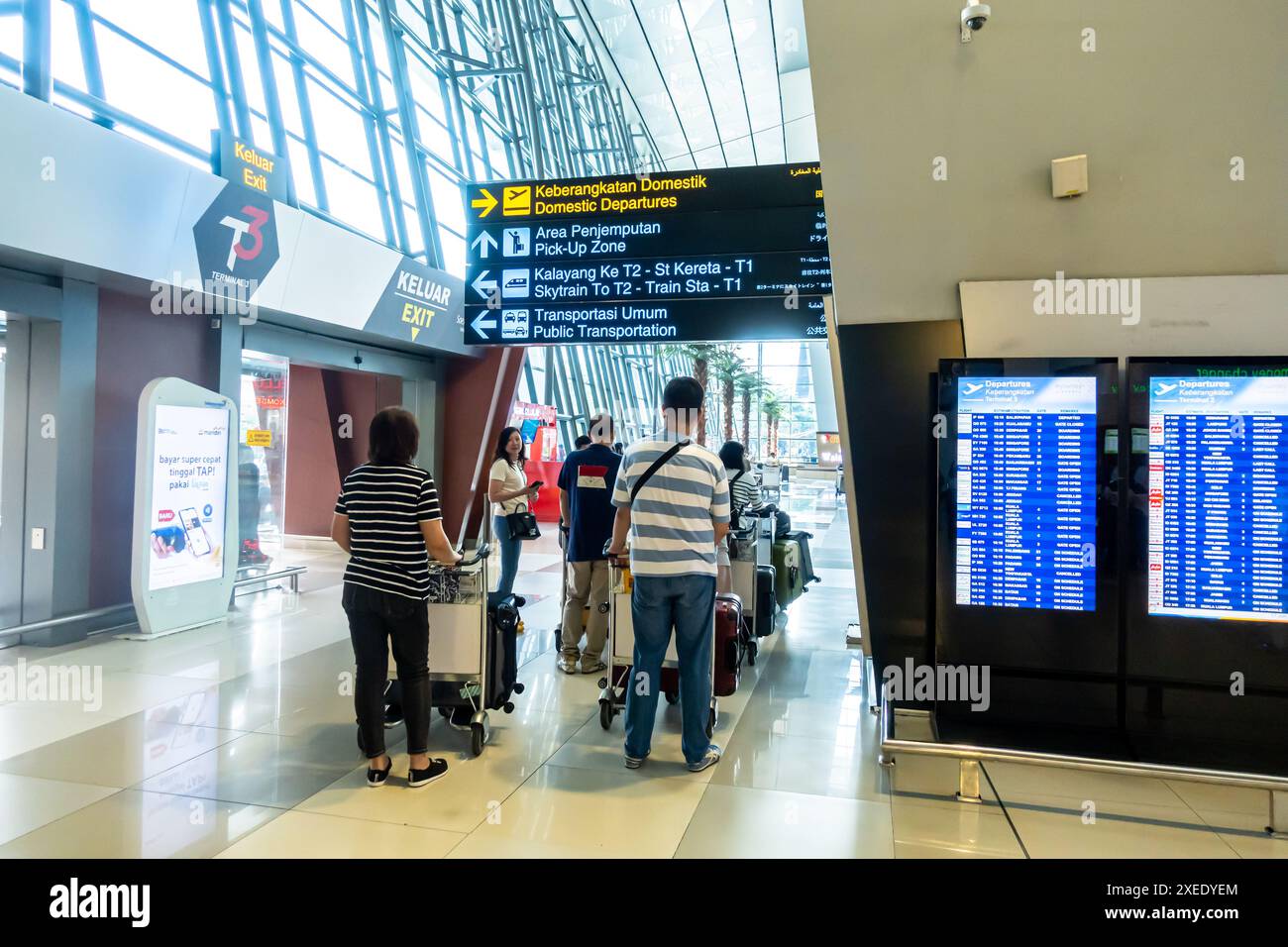 Touristen im Ankunftsterminal des CGK Soekarno-Hatta International Airport Jakarta Indonesien. Zweisprachige Richtungsschilder Stockfoto
