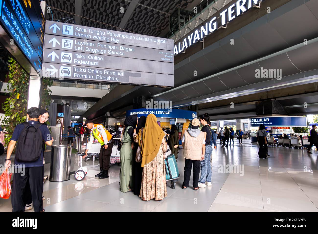 Touristen vor dem Ankunftsterminal im CGK Soekarno-Hatta International Airport Jakarta Indonesien. Zweisprachige Richtungsschilder Stockfoto