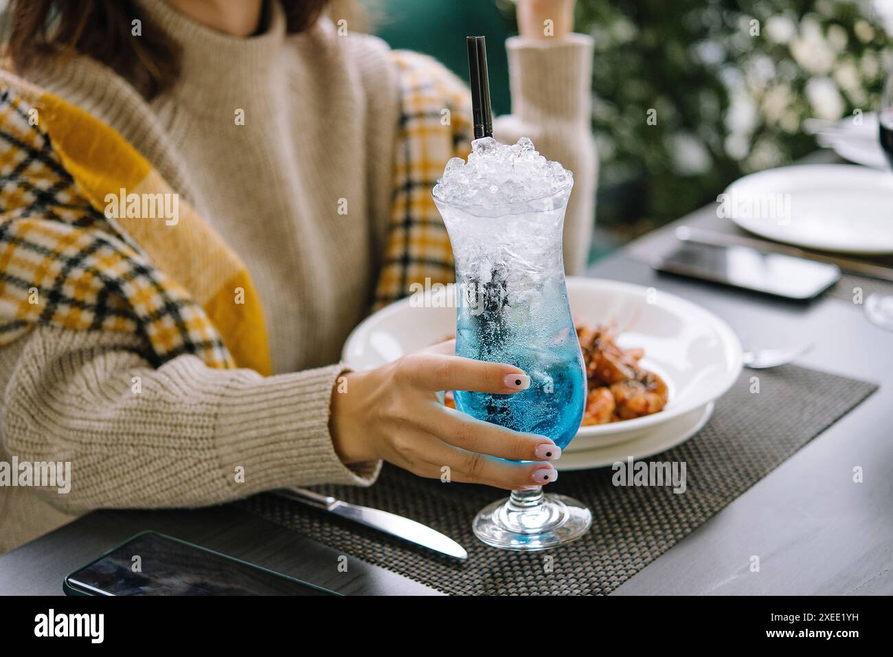 Eine junge Frau trinkt blauen Lagunencocktail Stockfoto