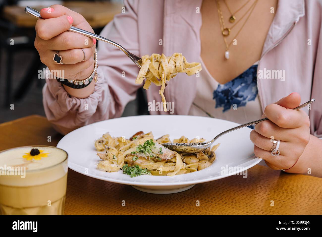 Frau isst Pasta mit Pilzen auf Holztisch Stockfoto