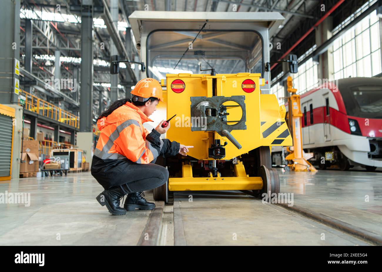 Weibliche Ingenieurin, die in einer Elektrobahn-Werkstatt arbeitet und kleine Schleifarbeiten an der Schienenmaschine überprüft, bevor sie eingesetzt wird Stockfoto