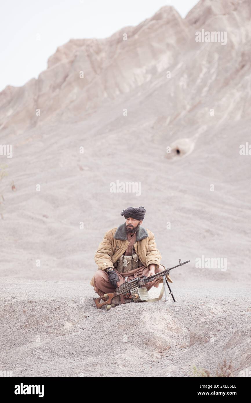 Ein Taliban-Soldat mit einem Maschinengewehr in der Wüstenlandschaft Stockfoto