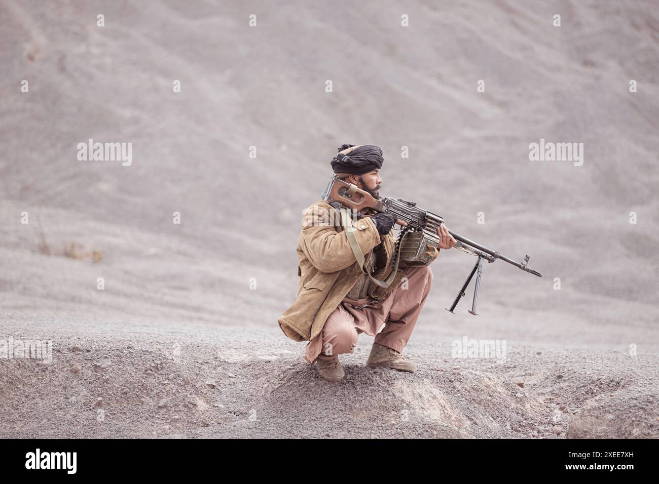 Ein Taliban-Soldat mit einem Maschinengewehr in der Wüstenlandschaft Stockfoto