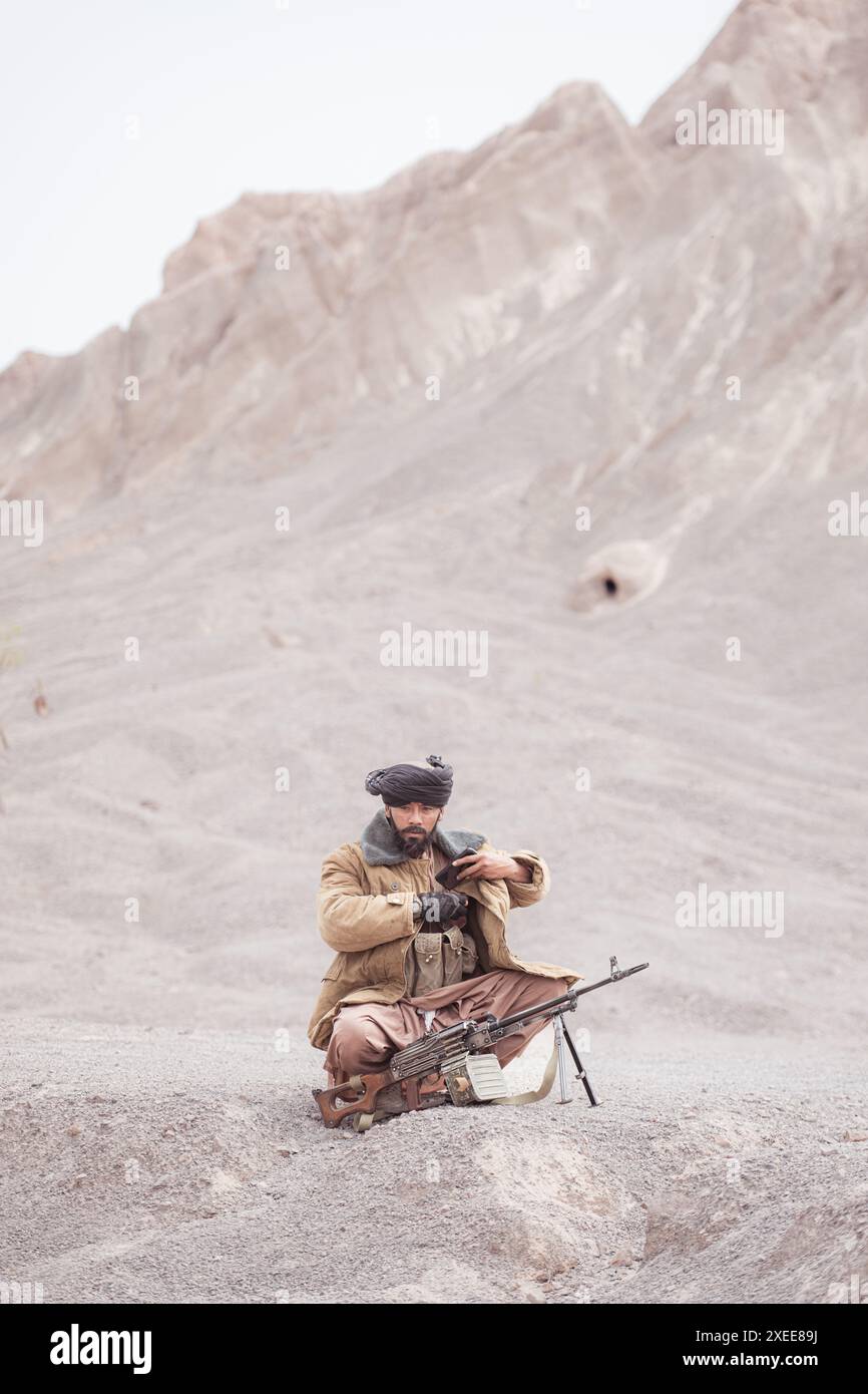 Ein Taliban-Soldat mit einem Maschinengewehr in der Wüstenlandschaft Stockfoto