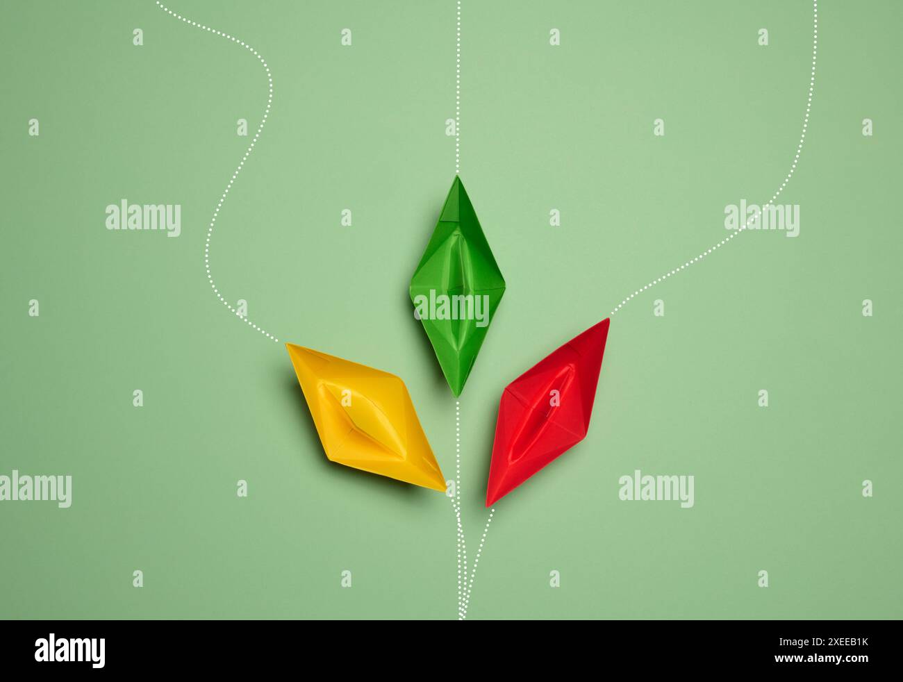 Papierboote auf grünem Hintergrund mit Bewegungswegen, die das Konzept der Individualität repräsentieren Stockfoto