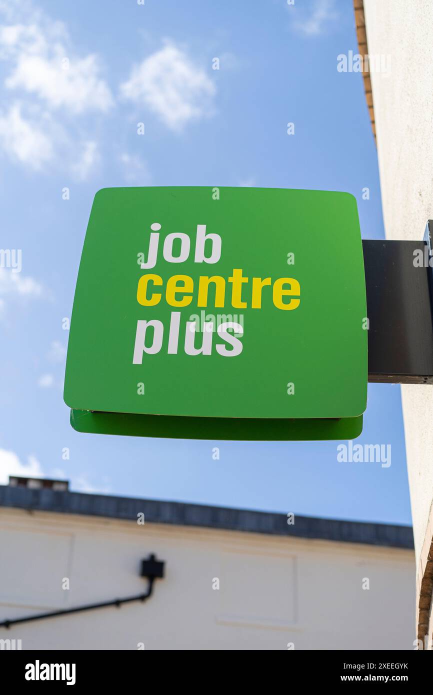 Nahaufnahme eines grünen Job Centre Plus-Schilds, das auf einem britischen Gebäude im Freien mit blauem Himmel isoliert ist. Stockfoto