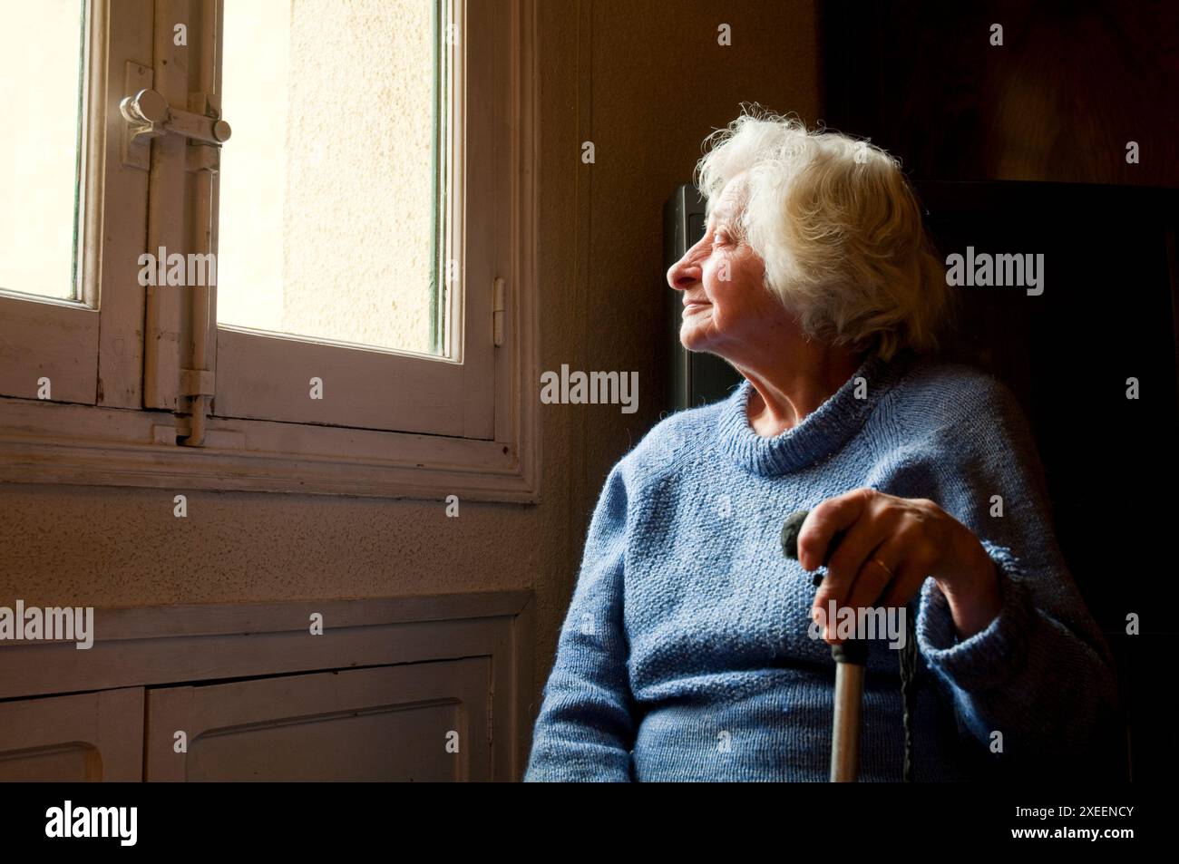 Porträt von alte Frau zu Hause, lächelnd und mit Blick auf das Fenster. Stockfoto