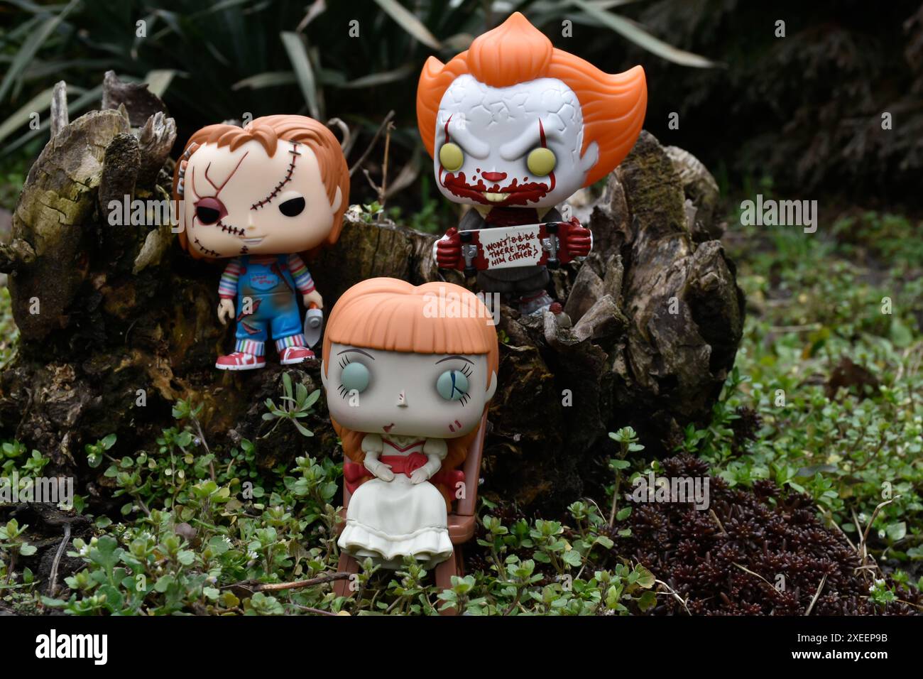 Funko Pop Actionfiguren aus Horrorfilmen. Pennywise böse Clown, gruselige Puppen Chucky und Annabelle. Moody, düster, gruseliger, dunkelgrüner Wald. Stockfoto