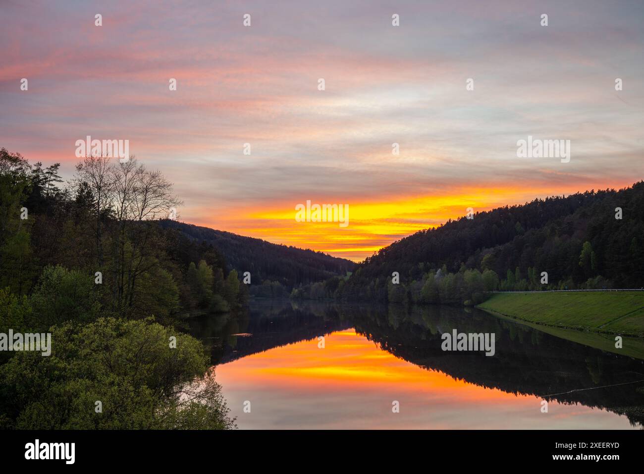Sonnenuntergang auf einem ruhigen See in einem Tal umgeben von einem Wald Marbachstausee Stockfoto