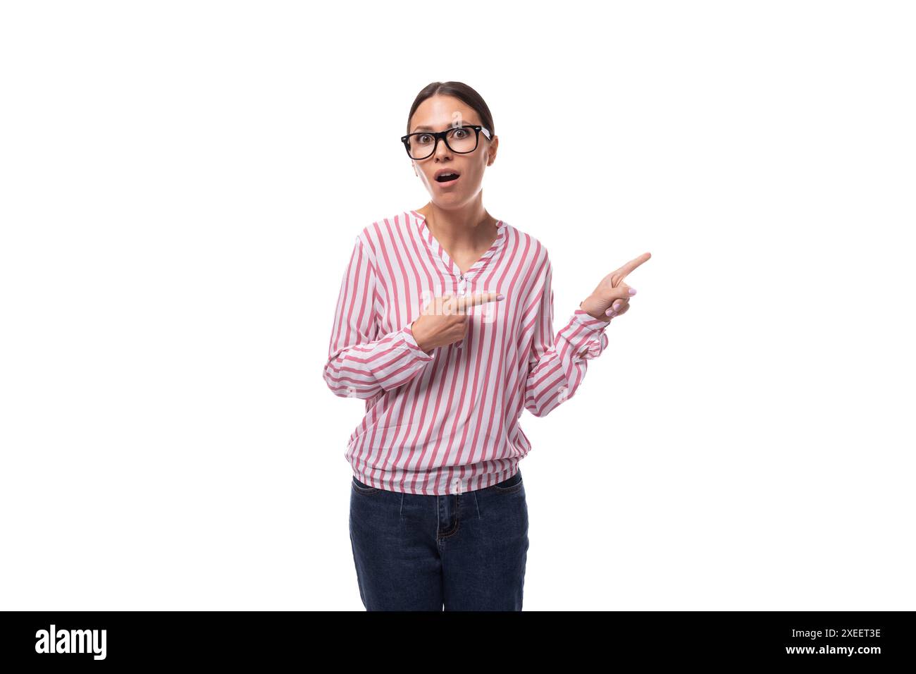 Die junge, freudige Büroangestellte in einem rosa-weißen Hemd zeigt auf einen leeren Raum Stockfoto