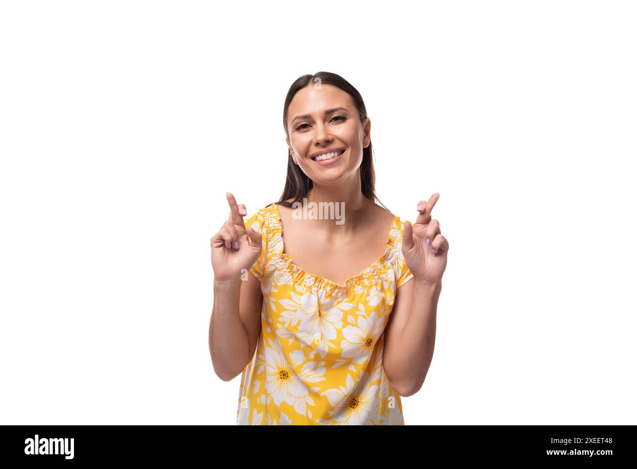 Europäische selbstbewusste Brünette mit lockeren Haaren, die ein gelbes T-Shirt auf weißem Hintergrund mit Kopierraum trägt Stockfoto