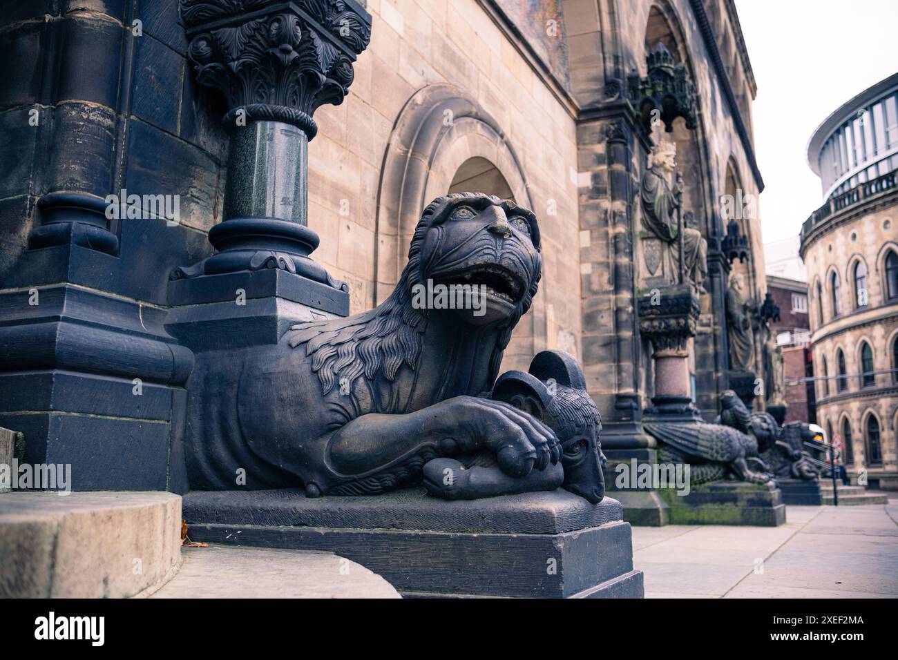 Ein dekoratives Monster aus Stein bewacht den Eingang zu einer alten mittelalterlichen katholischen Kathedrale. Wunderschöne Dekorationen und Basreliefs am Eingang Stockfoto