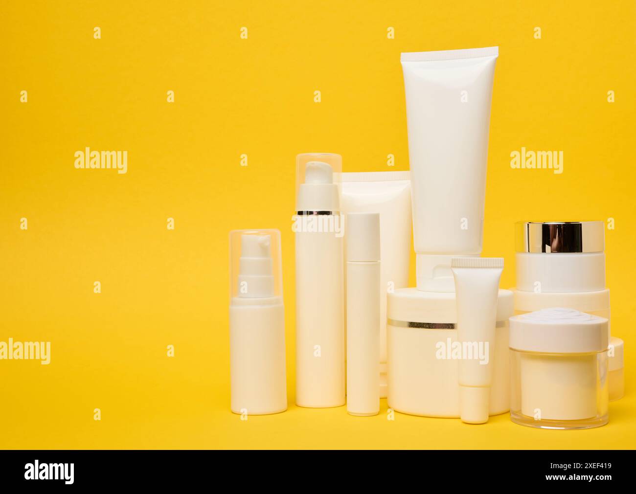 Verschiedene Arten von weißen Kunststoffverpackungen, Flaschen, Gefäße, Röhrchen auf gelbem Hintergrund. Behälter für Kosmetik Stockfoto