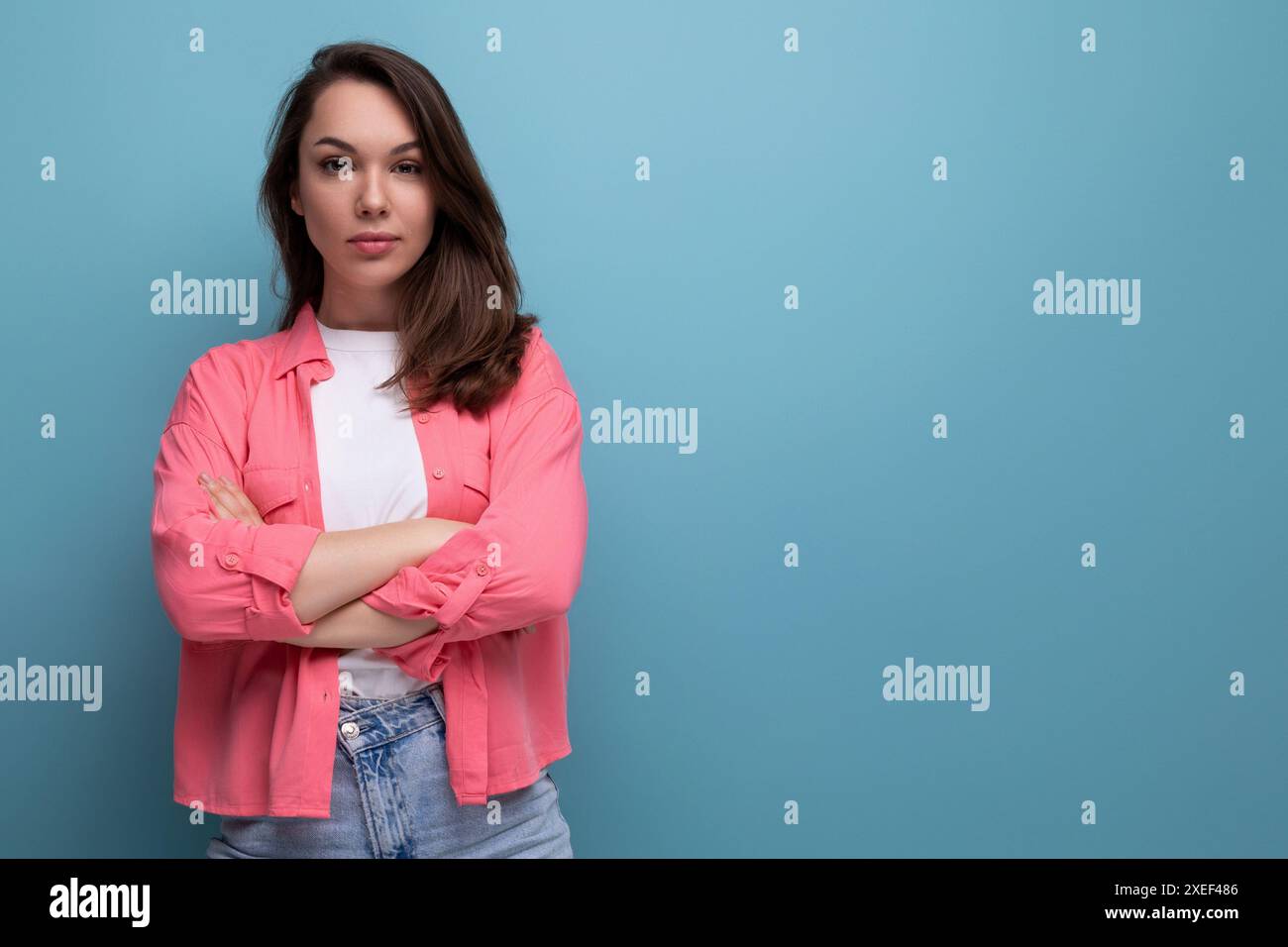 Porträt einer gut gepflegten jungen schwarzhaarigen europäischen Frau mit schulterlangen Haaren in einem rosa Hemd auf einem Atelierhintergrund wi Stockfoto