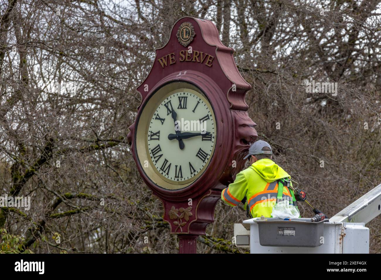 Vancouver, British Columbia, Kanada. April 2024. Eine Nahaufnahme eines Arbeiters in Vancouver, der eine öffentliche Uhr im Freien repariert Stockfoto