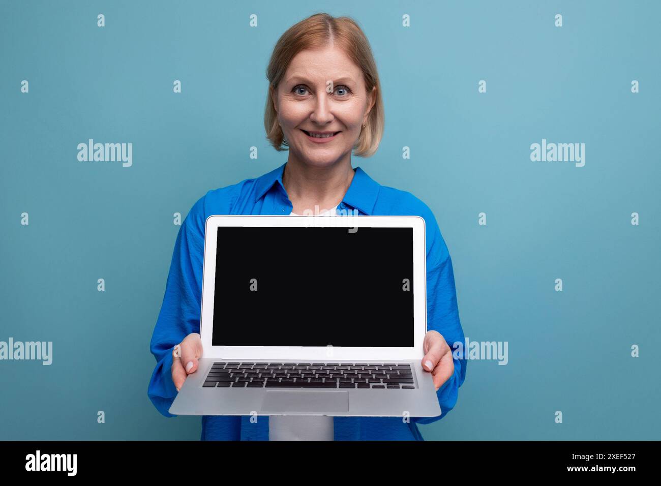 Erfolgreiche Geschäftsfrau erlernt einen Beruf aus der Ferne mit einem Laptop auf blauem Hintergrund und Kopierraum Stockfoto