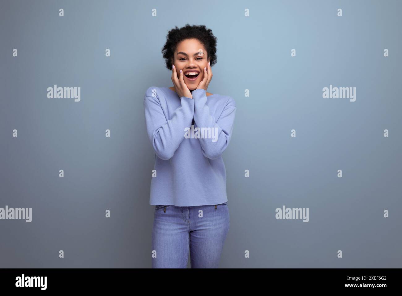Positive energiegeladene junge brünette latinfrau mit Afro-Locken in stilvoller Frühlingskleidung auf isoliertem Hintergrund Stockfoto