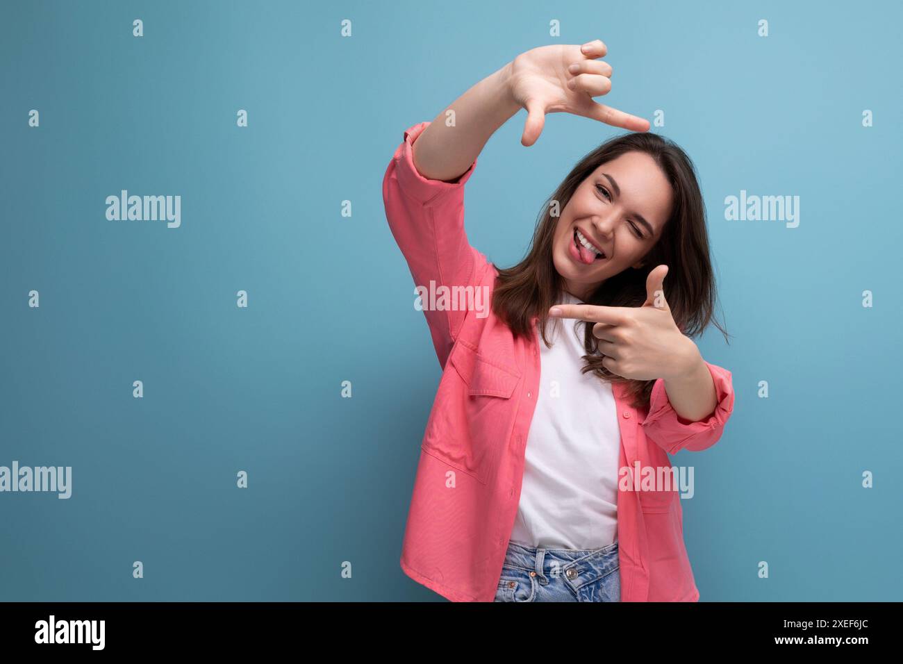 Moderne brünette Frau in rosa Hemd macht Fotos mit Telefon auf Studiohintergrund Stockfoto