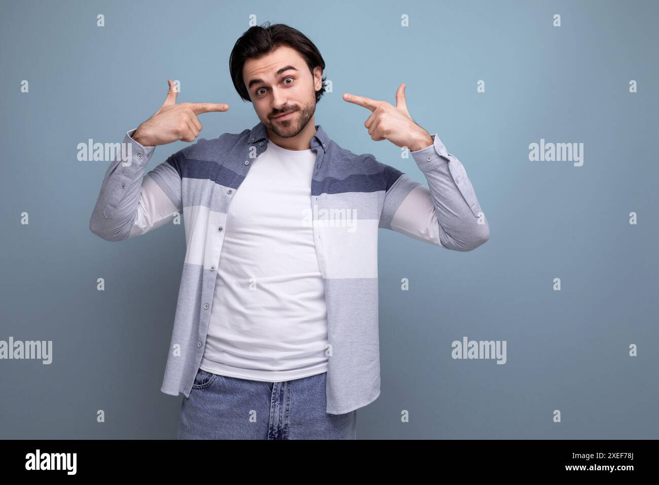 Ein netter Brünette-Typ im lässigen Stil zeigt mit seiner Hand, weil er eine Idee auf einem Studiohintergrund hat Stockfoto