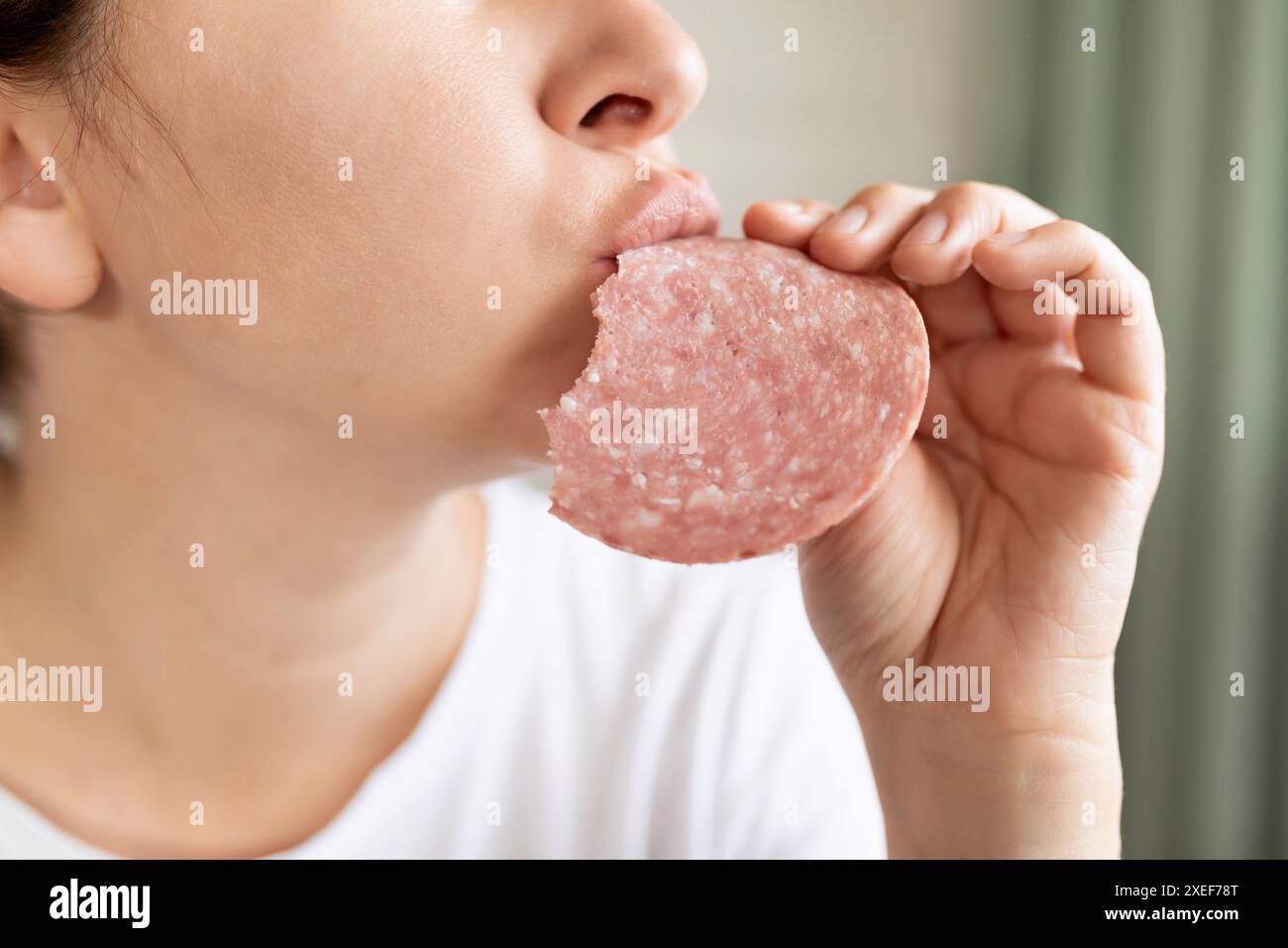 Eine junge Frau, die zum Frühstück Würstchen aus dem Supermarkt isst Stockfoto
