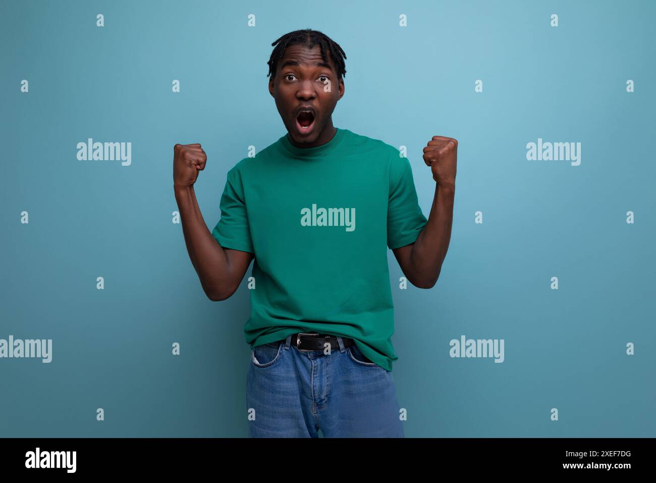 Selbstbewusstes Brünette-Modell stilvoller dunkelhäutiger Mann in Dreadlocks in einem coolen T-Shirt auf blauem Hintergrund Stockfoto
