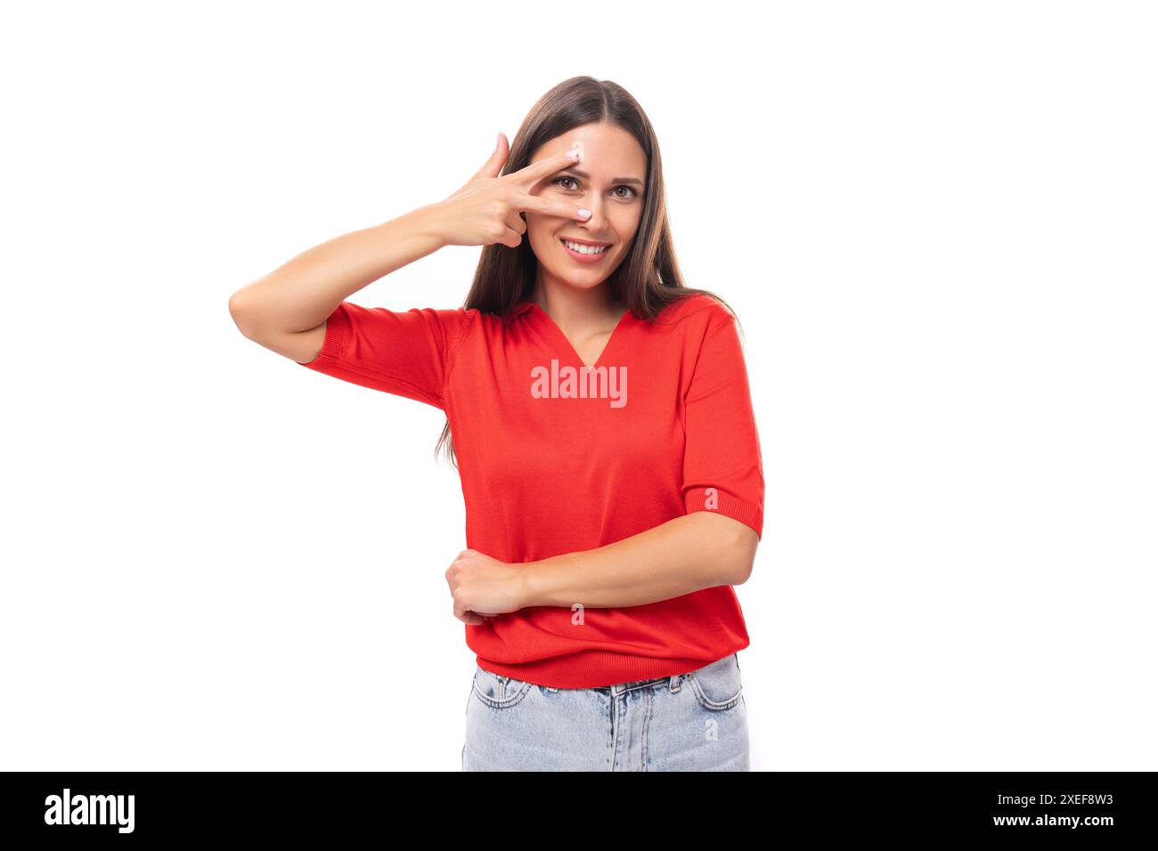 Die junge charmante Brünette, die in einem roten T-Shirt gekleidet ist, lächelt süß auf weißem Hintergrund Stockfoto