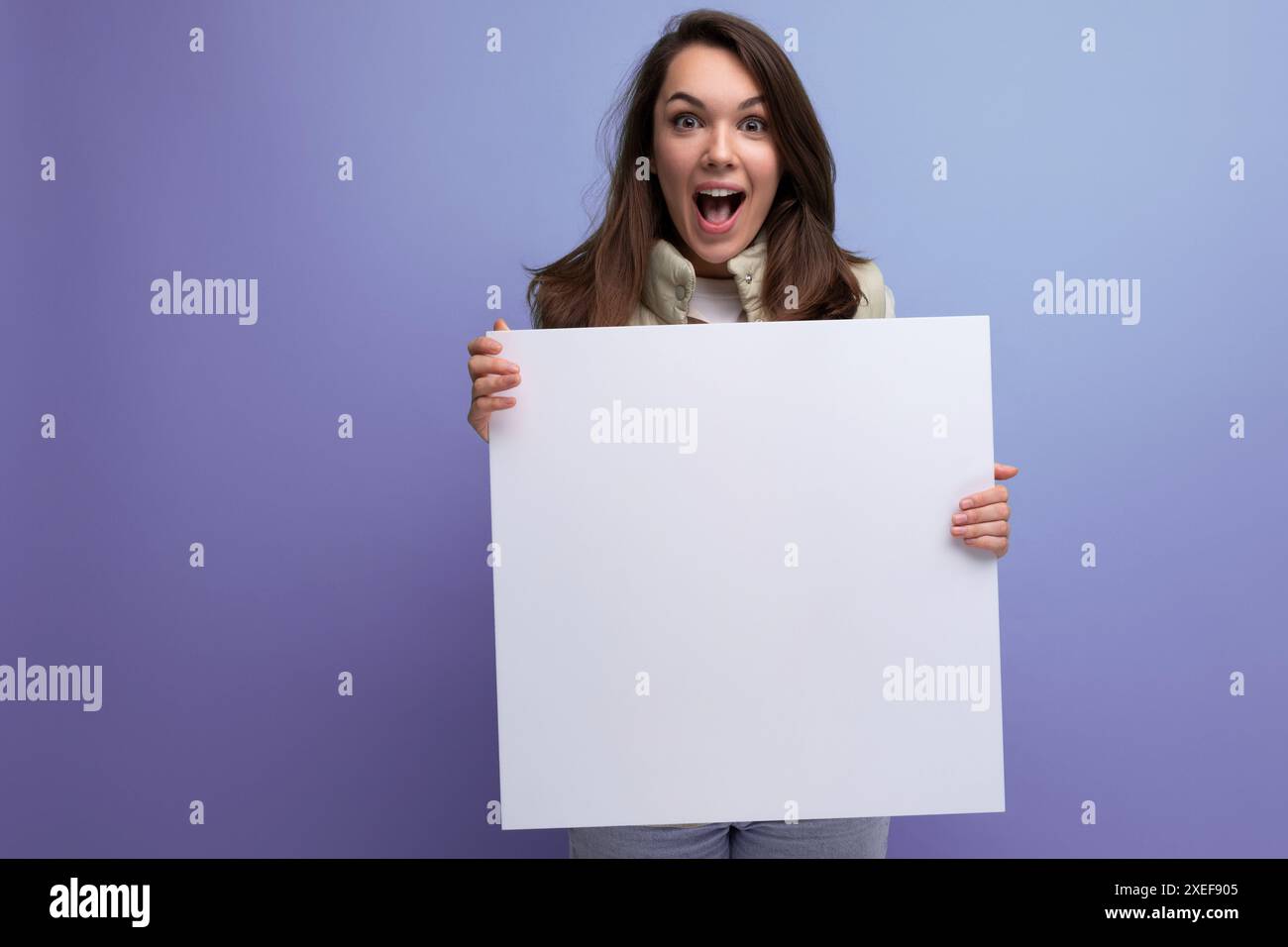Glückliche junge brünette Frau, die Pappkarton mit Mockup hält Stockfoto