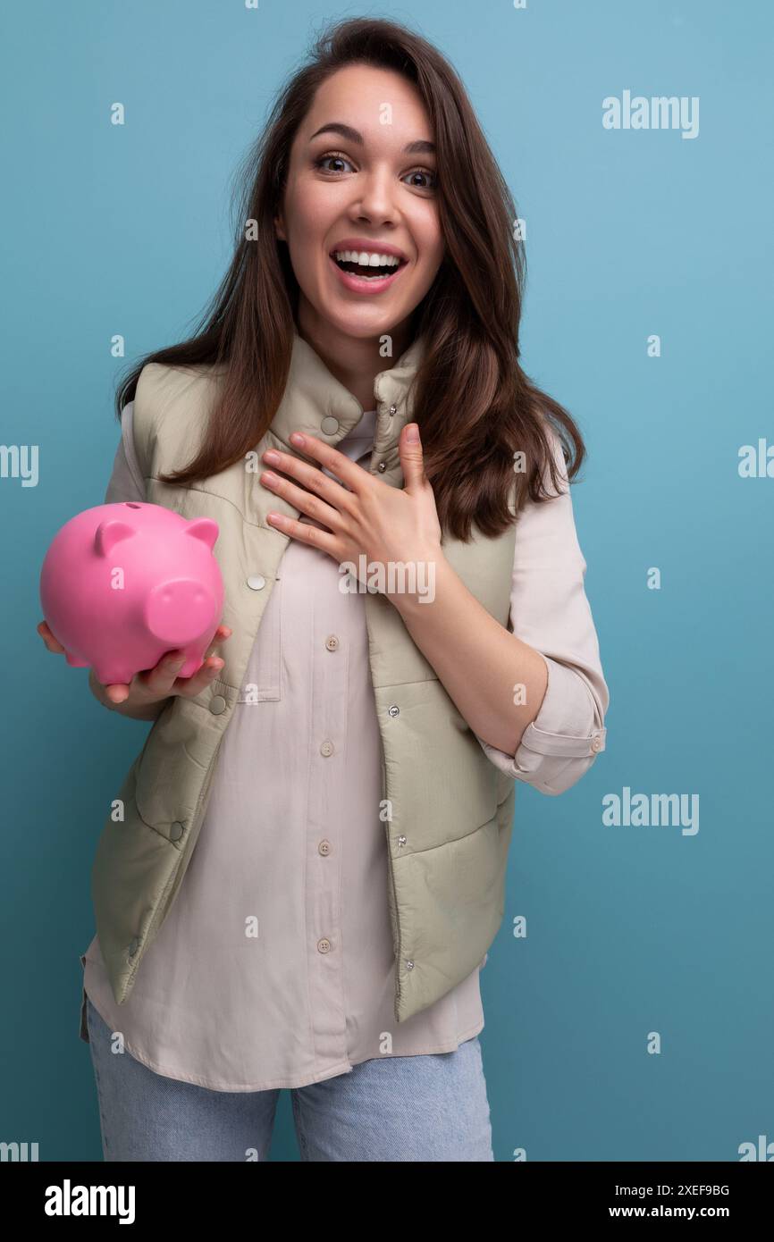 Glückliche junge brünette Frau, die rosa Spargeld hält Stockfoto