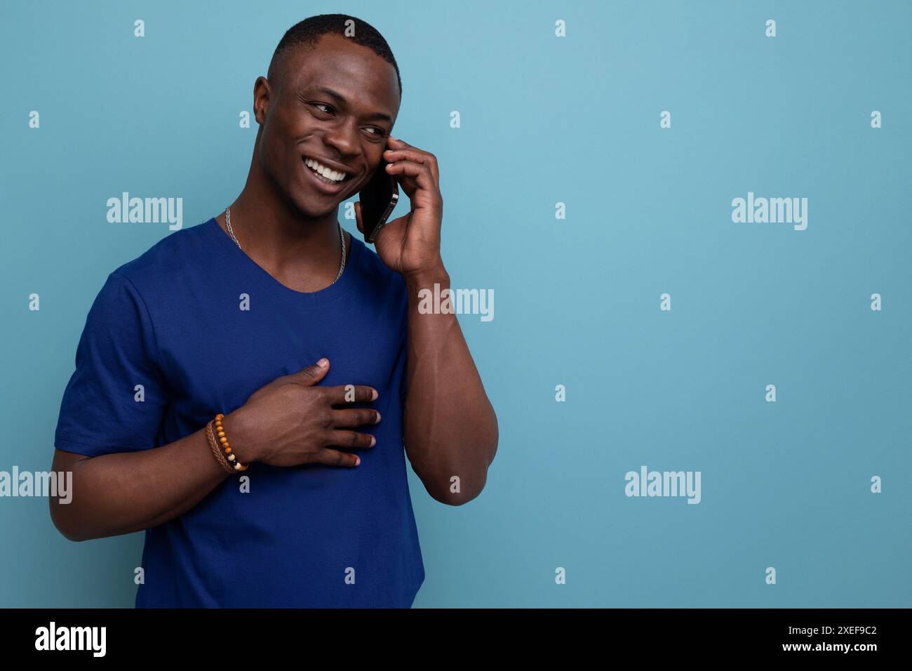 Junger amerikanischer Mann in blauem T-Shirt, der am Telefon spricht Stockfoto