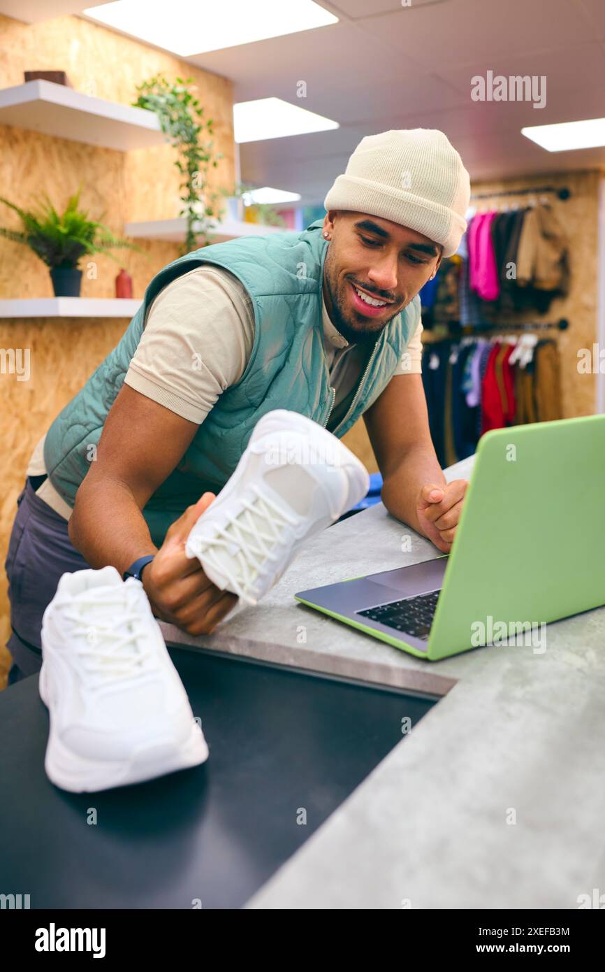 Männlicher Verkaufsassistent An Der Kasse In Pop-Up-Mode- Oder Kleiderläden, Der Ein Paar Turnschuhe Verkauft Stockfoto