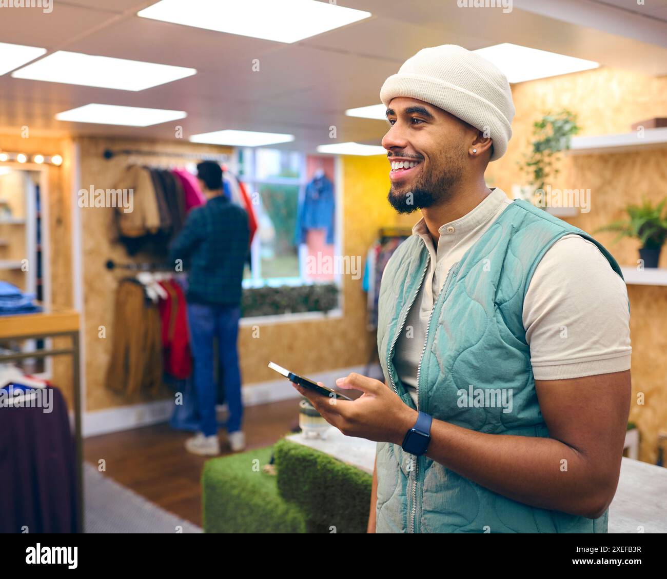 Männlicher Vertriebsmitarbeiter Oder Kunde Im Pop-Up-Mode- Oder Kleidergeschäft, Der Sich Ein Mobiltelefon Anschaut Stockfoto