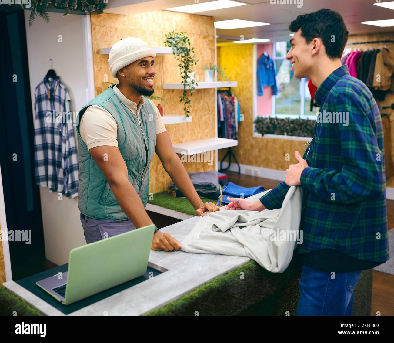 Männlicher Kunde, Der Einen Pullover Von Einem Vertriebsassistenten An Der Kasse Im Pop-Up-Mode- Oder Kleiderladen Kauft Stockfoto