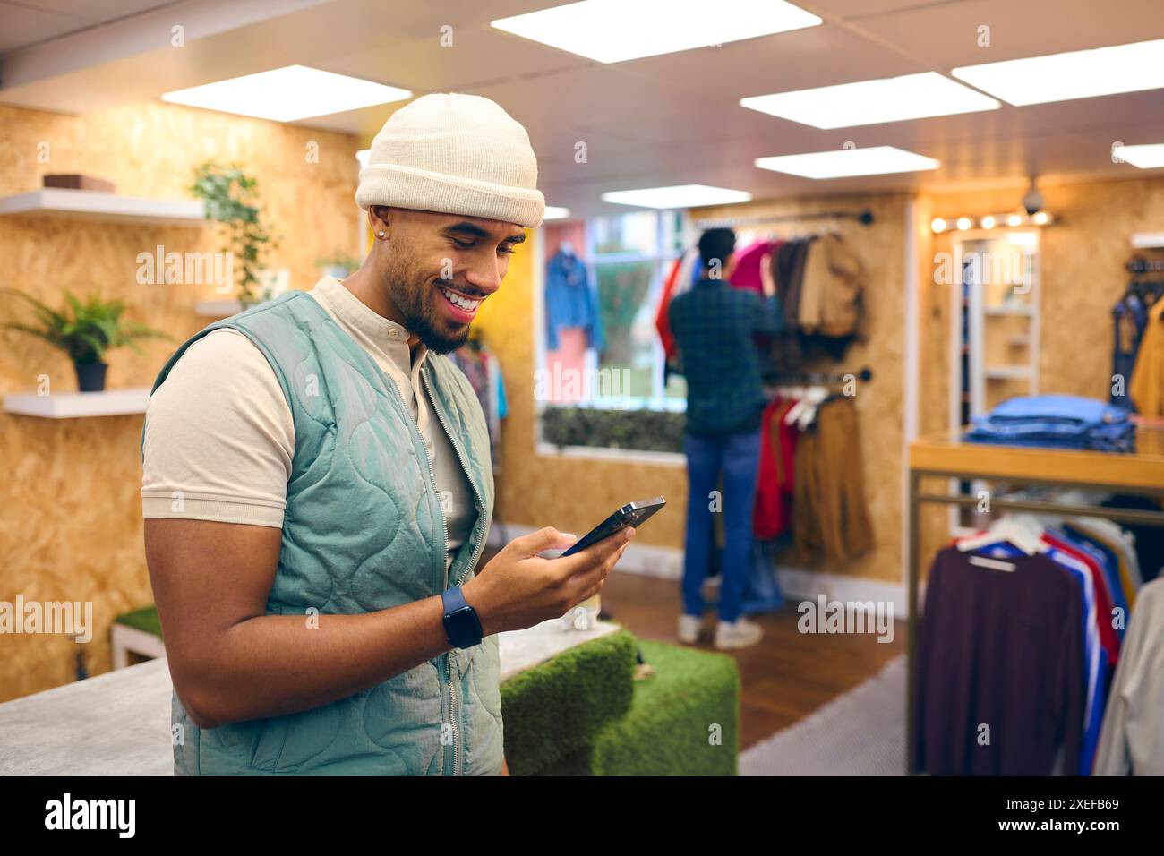Männlicher Vertriebsmitarbeiter Oder Kunde Im Pop-Up-Mode- Oder Kleidergeschäft, Der Sich Ein Mobiltelefon Anschaut Stockfoto